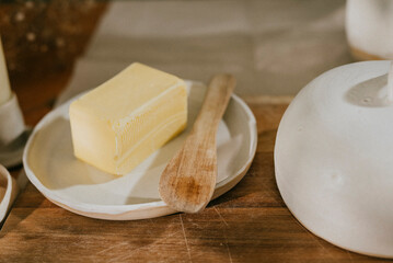 A butter knife sits on a plate with a slice of butter on it. The scene is simple and unpretentious, with the focus on the butter and the knife