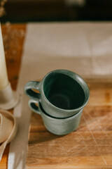 Two green cups sit on a wooden table. The cups are empty and the table is made of wood