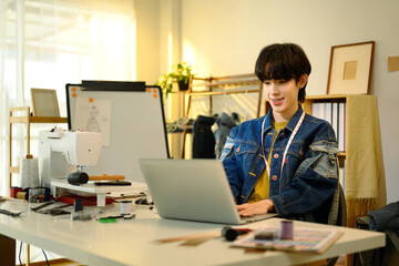 Fashion designer working on laptop in a creative studio