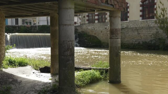 View on the river Le Saleys and on pilars holding a very ancient house in Salies-de-B&eacute;arn. Waterfall in the background.