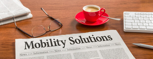 A newspaper on a wooden desk - Mobility Solutions