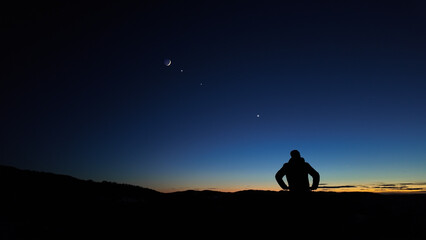 Silhouette of a man observing Milky Way stars, planets and other celestial objects from a dark...
