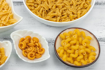Pasta. Various kinds of uncooked pasta and noodles over wooden background