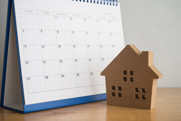 House and blank wite calendar on wooden table with white wall background. Mortgage loan, home...