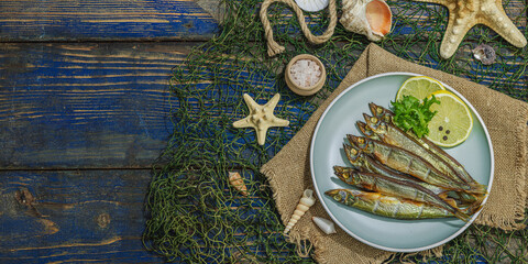 Smoked smelt with fresh lemon and herbs. Salted fish with marine decor. Trendy dish, sea rope
