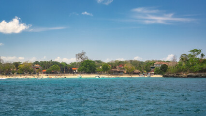 Obraz premium A tropical beach scene features clear blue waters, soft white sand, lush green trees, and a vibrant sky, creating a breathtaking contrast that captivates, Nusa Lembongan, Bali, Indonesia