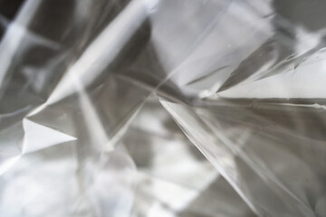 Crumpled clear plastic background, abstract glossy broken surface texture with creases
