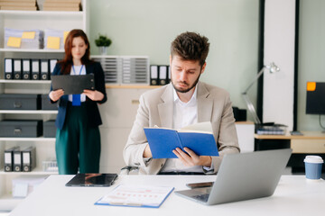 Fototapeta premium Two business workers talking on the smartphone and using laptop
