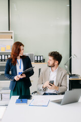 Two business workers talking on the smartphone and using laptop