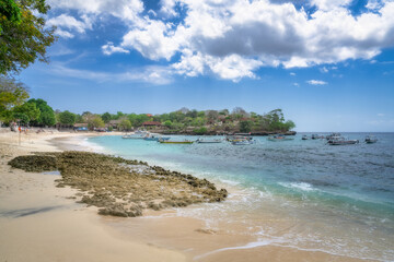 Imagine a picturesque tropical beach boasting calm azure waters, colorful boats, lush vibrant greenery, and a bright clear blue sky that all enhance the stunning view, Nusa Lembongan, Bali, Indonesia
