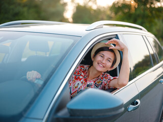 Traveler woman in red ethnic dress and hat drives car through scenic countryside of Croatia in summer. Surrounded by lush fields and forests, she enjoys peaceful and adventurous road trip