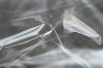 Crumpled clear plastic background, abstract glossy broken surface texture with creases