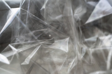 Crumpled clear plastic background, abstract glossy broken surface texture with creases