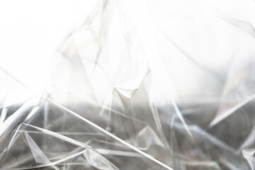Crumpled clear plastic background, abstract glossy broken surface texture with creases