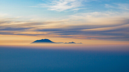 Silhouette of the mountain above the thick fog at sunrise with colorful sky, creating an atmosphere...