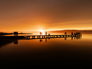 Fototapeta premium Golden Sunset Over the Ebro Delta Pier, Catalonia, Spain: Silhouettes Reflected in Tranquil Waters