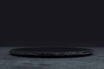 Round rustic black slate stone plate, on stone background