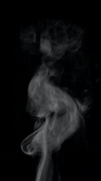 White natural rising steam from food or hot drink isolated on a black background. Сan be used in any projects with hot food. Slow motion vertical template.