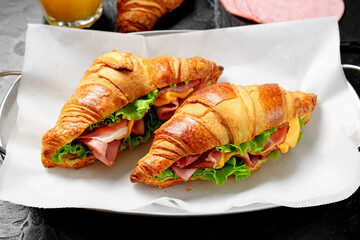 Two Fresh croissant sandwiches with ham, cheese and salad leaf.