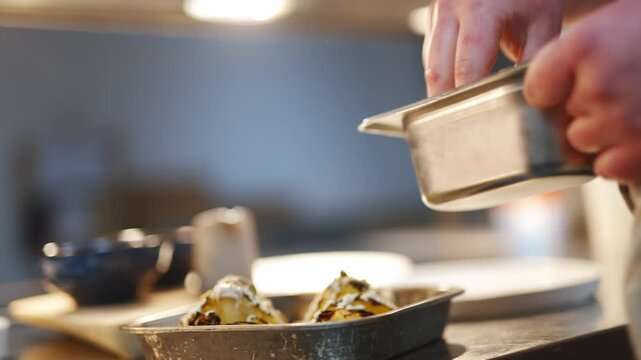 A chef sprinkling salt on food. Concept of focus and attention to detail as the chef carefully adds the seasoning to the dish. The scene suggests a moment of preparation
