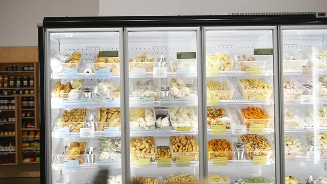 A large display of food in a store with a sign that says "Fresh". The food is in a freezer and includes items such as bread, cheese, and vegetables
