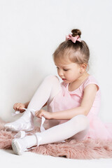 Little girl in a tutu skirt tying her ballet shoes