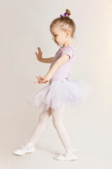 Cute little toddler in ballet costume practicing, high key