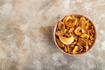 Dried Apples in ceramic bowl on brown concrete. Top view, copy space