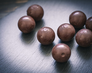 Edle Schokoladenkugeln auf schwarzer Schieferplatte