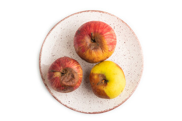 Decaying, Rotting apples on ceramic plate isolated on white. Top view, copy space