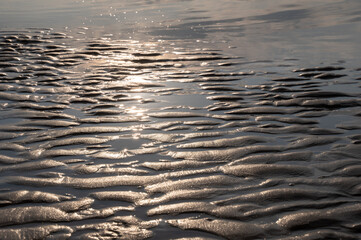 Wet sand by the sea at sunset