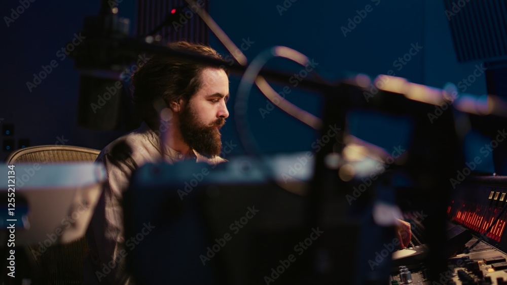 Poster Music engineer working in professional studio control room to do mix and master on audio recordings, editing tunes. Sound technician using sliders and faders on board, stereo equipment. Camera B.