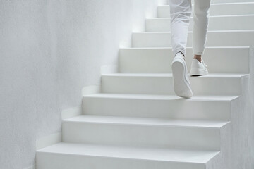 Businessman climbing white stairs in modern minimalist building
