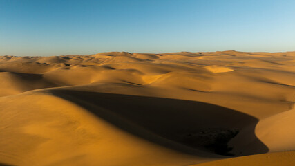 Aerial drone view of the ocean shore beaches next to the Namib dunes on a beautiful day of adventure at sunset, Namibia, Africa