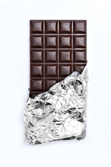Chocolate bar partially wrapped in silver foil on a white background. The rich, dark brown chocolate contrasts with the shiny metallic wrapper.