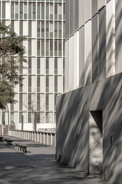 Concrete pathway bordered by modern buildings with textured facades and strong shadow contrasts in an urban environment.