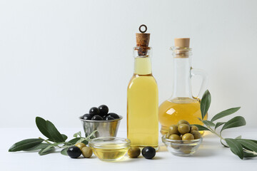 Bottle of fresh olive oil and olives with leaves on the table 