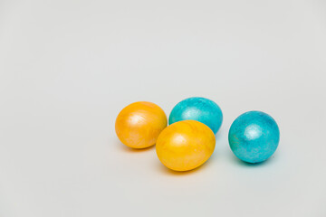 Four brightly colored Easter eggs, two yellow and two blue, arranged in a random pattern on a white background, creating a festive and playful composition.