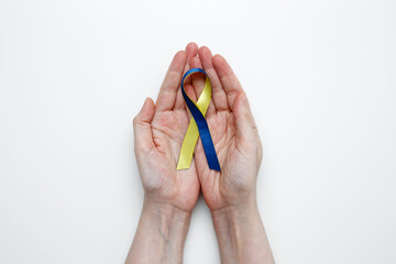 A person holds a yellow and blue awareness ribbon, symbolizing World Down Syndrome Day