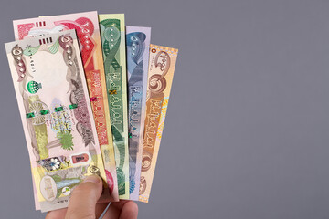 Iraqi money in the hand on a gray background