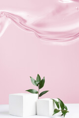  Two cement cubic podiums and green leaves of ruscus on a pink gel background. Mockup for the demonstration of cosmetic products. 