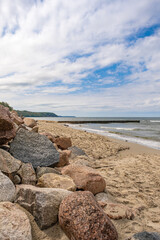 Emerald sea and blue sky on a warm summer day. Wooden buns extending into the sea and white sand. Baltic Sea, soft focus. The concept of travel, tourism