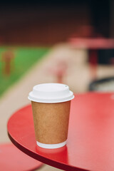 Paper cup of coffee take away on urban background. Time for drink coffee in city. Coffee to go, take a break. Disposable paper cup closeup. Blank space for text, mockup