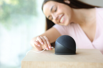 Happy woman plugging charger to her smart speaker