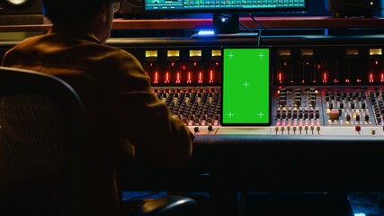 African american audio technician mixing and editing tracks with greenscreen on tablet, working in...