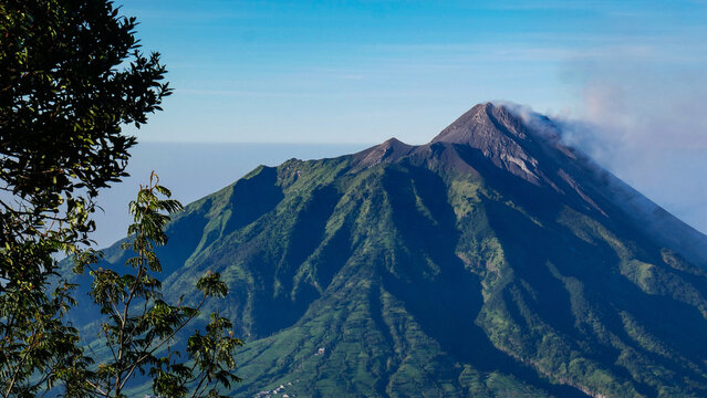 View of Mount Merapi from the Mount Merbabu hiking trail, with a peak filled with sand and rocks that always emit volcanic smoke from its crater.