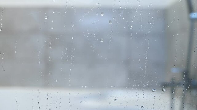 A close-up of water droplets on a transparent glass surface, creating a soft and blurred background. The video captures the detail of condensation, evoking a sense of humidity and moisture.