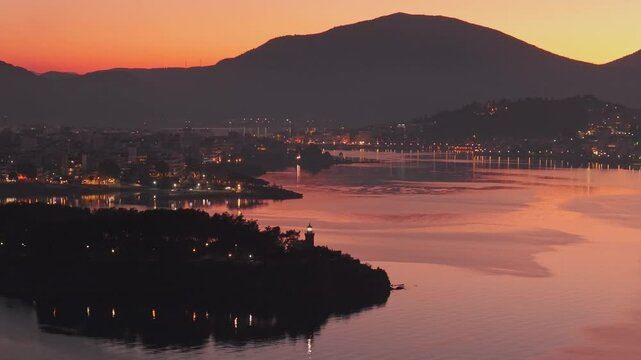 A unique golden-pink sunset over Chalkida city, with a view of the lighthouse shining and the old bridge