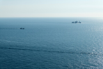 rock and boats on the sunlight-reflected sea