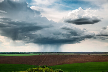 A stormy and rainy gray cloud with a visible streak of rain floats across the sky.